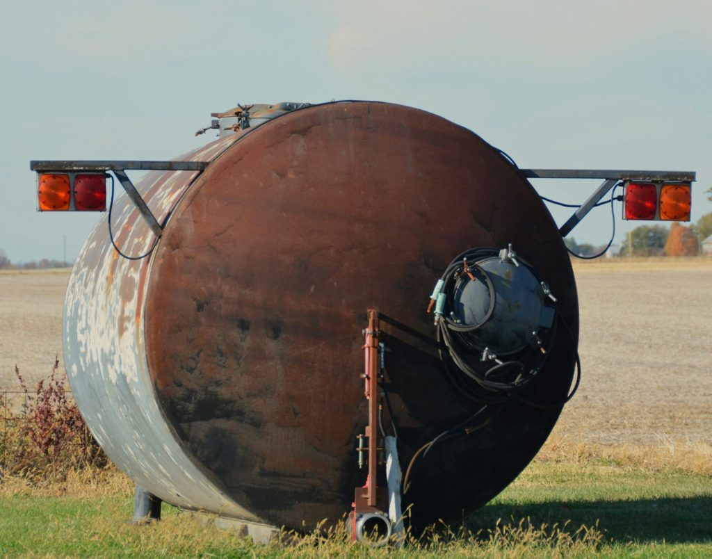 Depósito de agua oxidado con luces rojas en un campo